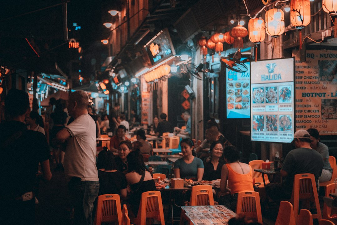 Menschen an kleinen Tischen und Streetfood-Ständen in Hanois Nachtmarkt